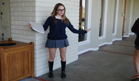 Erika '15 struts down the hallway in her shiny black rain boots.