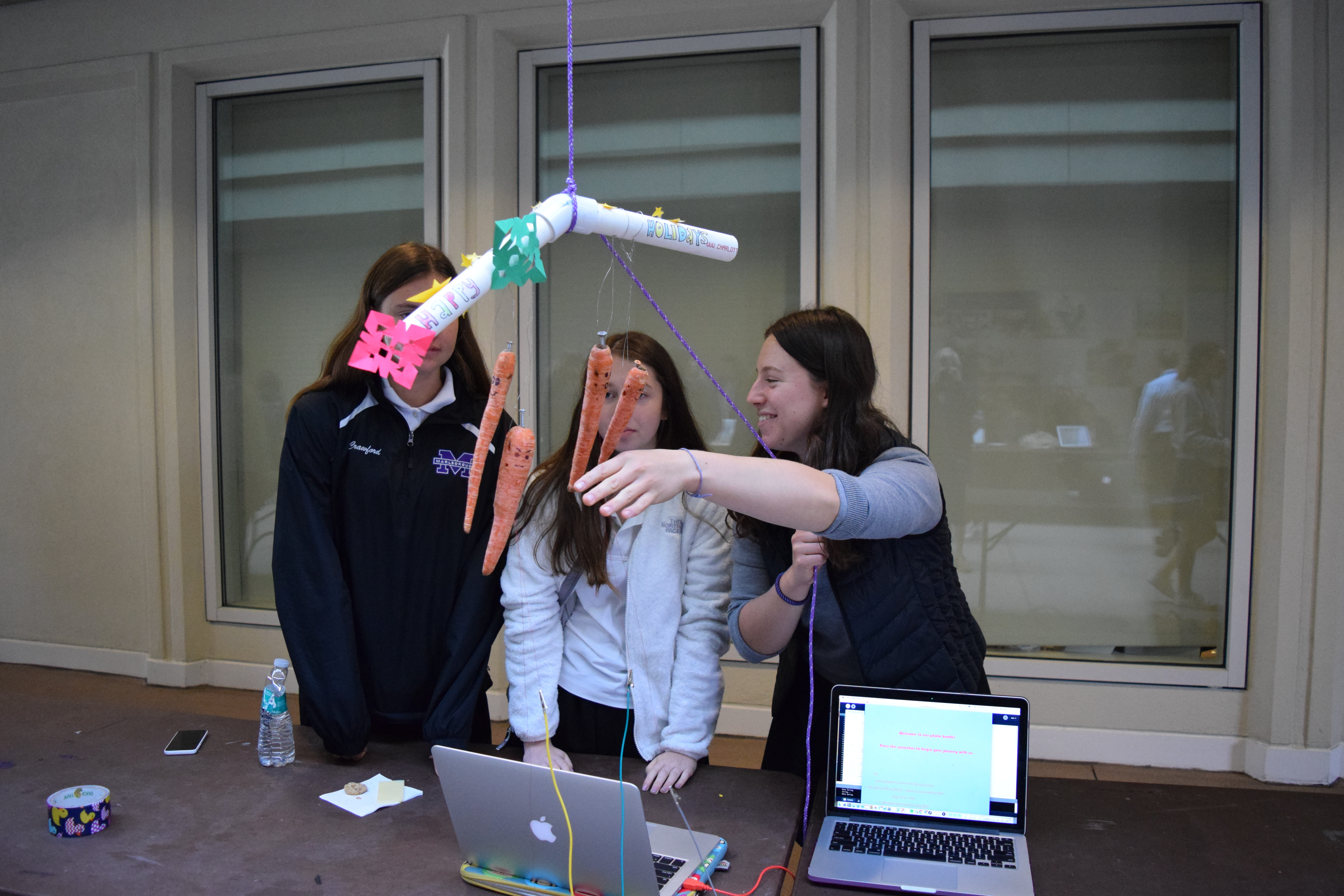 Megan '19, Eve '19 and Rachel '19 demonstrate how to use their carrot wind chime.