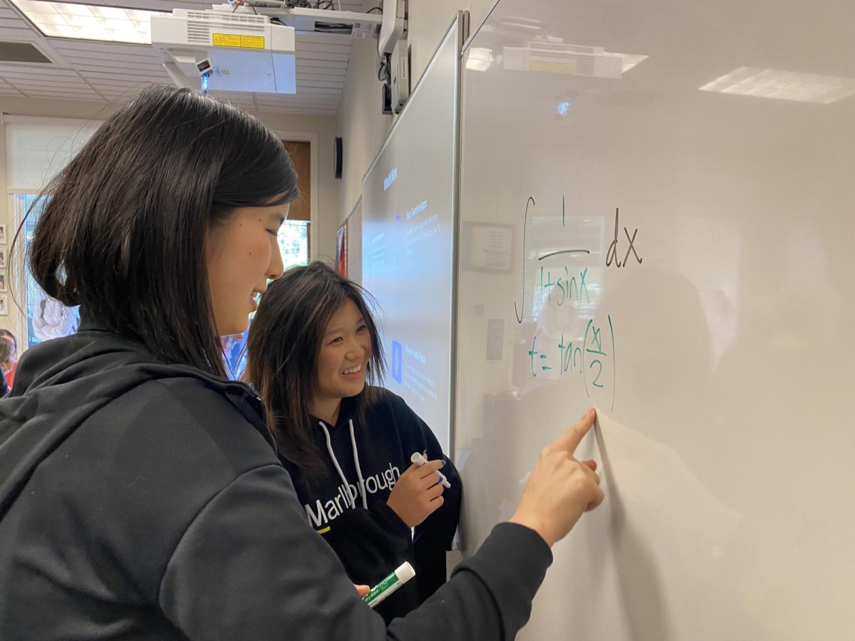 Rachel ’26 and Ava ’25 collaborate to solve a mathematical equation on the board.