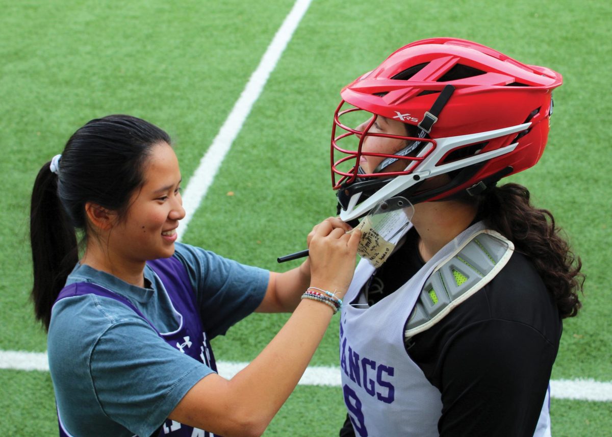Lily ’25 signs the helmet of Aubrey ’26 before practice.
Dinah 25 Staff Photographer