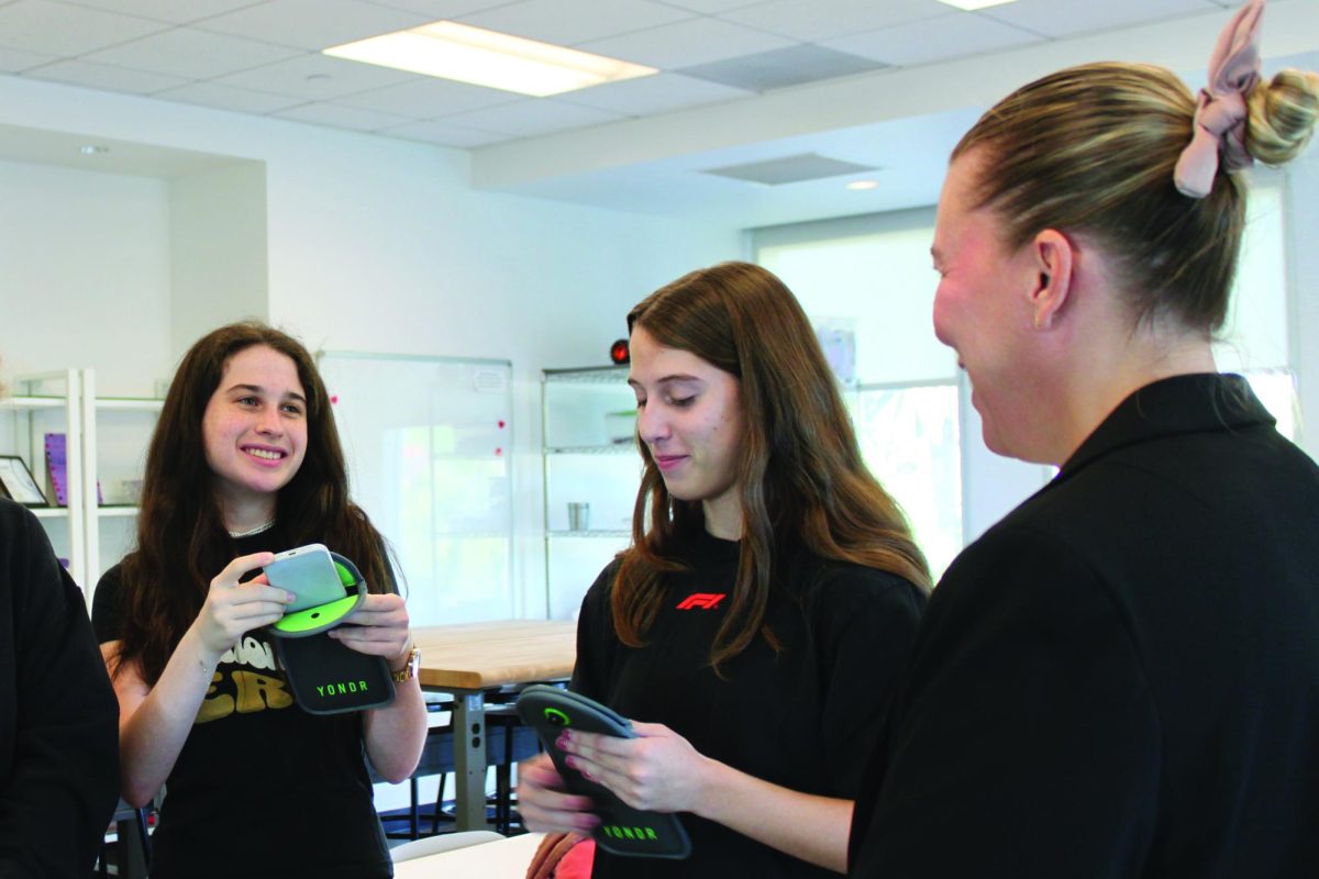 Phoebe ’25 and Sabrina ’25 pouch their phones in the Yondr pouch in homeroom.