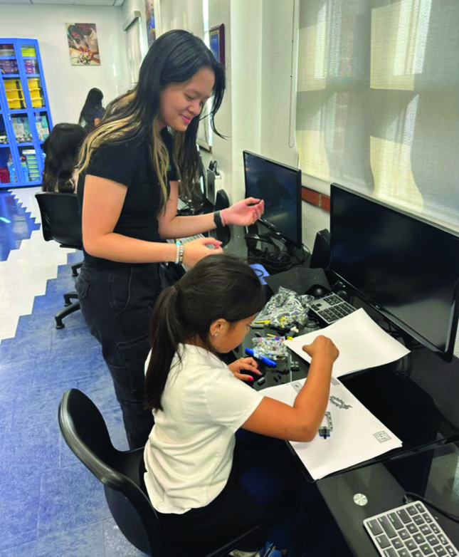 Chloe Tjo ’26 helps a student on Curiosity’s FLL team at the Boys and Girls Club build a Lego set.